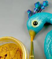 Clay peacock beak being painted with yellow colorant